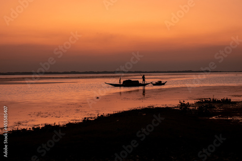 Silhouette of man standing on a boat near seashore during sunset photo