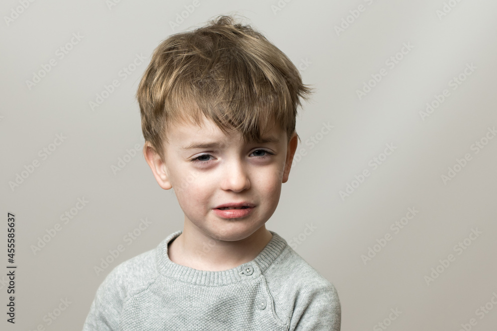 little boy of European appearance with a sad face. the baby is crying. gray background. emotions little boy of European appearance with a sad face. the baby is crying. gray background. emotions