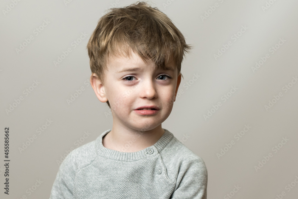 little boy of European appearance with a sad face. the baby is crying. gray background. emotions little boy of European appearance with a sad face. the baby is crying. gray background. emotions