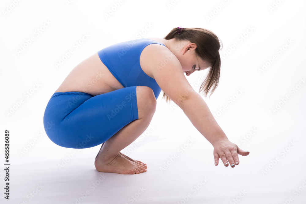 a girl of European appearance in a blue suit is engaged in fitness or yoga. White background. not a perfect figure. Sports training. squats side view. horizontal photography a girl of European appearance in a blue suit is engaged in fitness or yoga. White background. not a perfect figure. Sports training. squats side view. horizontal photography