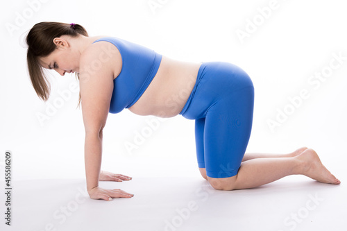 girl in a blue suit is engaged in fitness or yoga. White background. not a perfect figure. Sports training.