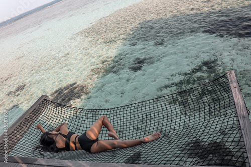 Woman in bikini lying on black net hammock at the beach photo