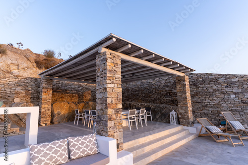 Trendy outdoor patio pergola shade structure, awning and patio roof, garden lounge and chairs.