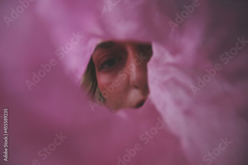 Woman looking through a hole in a oink textile photo