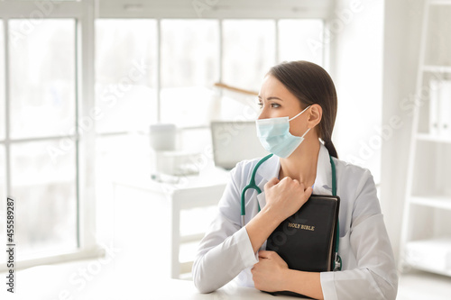 Praying female doctor in cl...