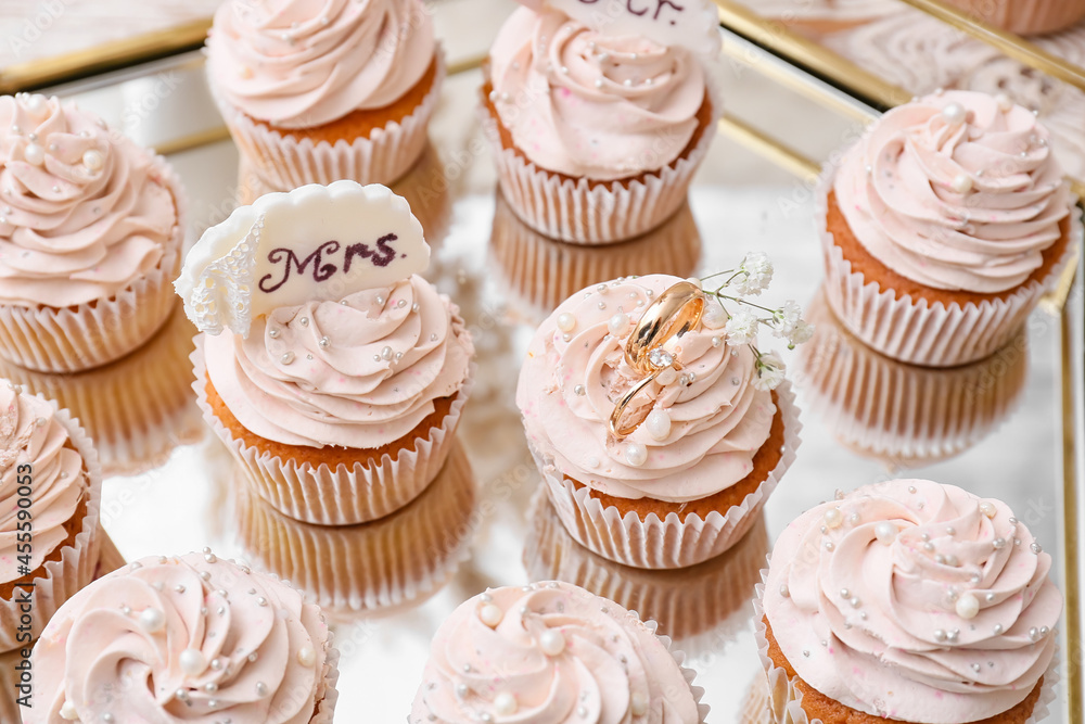 Tasty cupcakes and wedding rings on tray Tasty cupcakes and wedding rings on tray