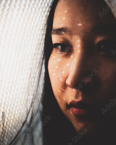 Woman with light textile on her head and light coming through photo