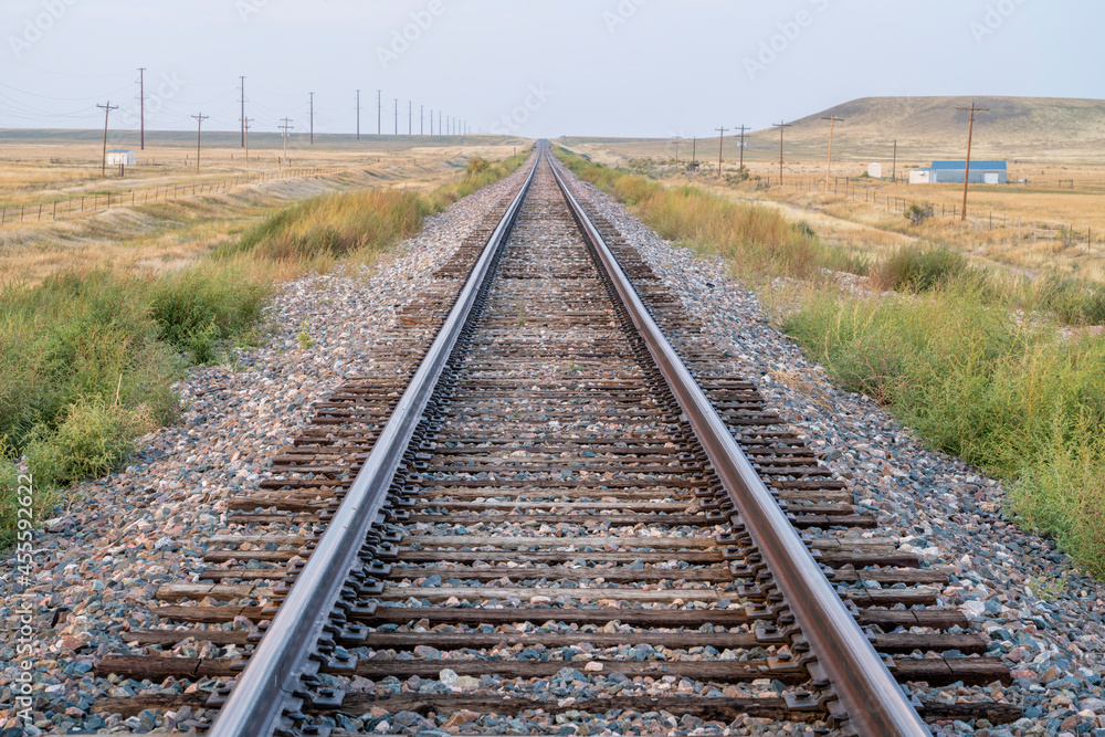 Obraz premium railroad tracks in a prairie of northern Colorado, late summer scenery with smoke and haze from distant wildfires - travel and transport concept