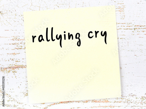 Valokuva Yellow sticky note on wooden wall with handwritten word rallying cry
