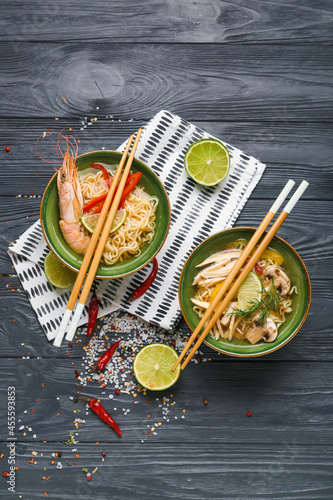 Bowls of tasty Thai soup with chicken and shrimps on dark wooden background