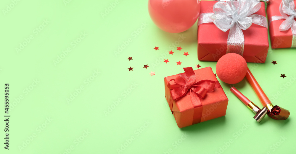 Gift box and noisemakers on color background