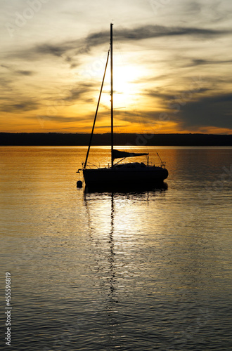 a scenic sunset on lake Ammersee with a sailing boat resting on the water (Herrsching on Ammersee in Germany)