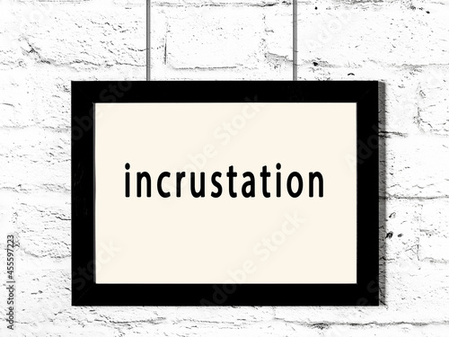 Black frame hanging on white brick wall with inscription incrustation