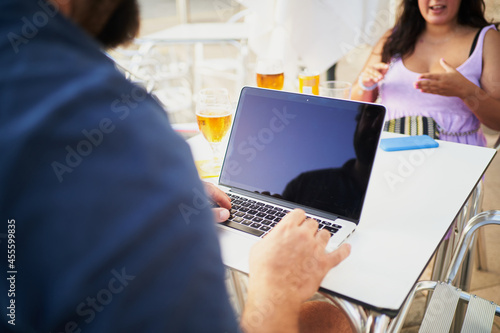 Unrecognizable bearded man and using computer in cafeteria outdoors talk with woman