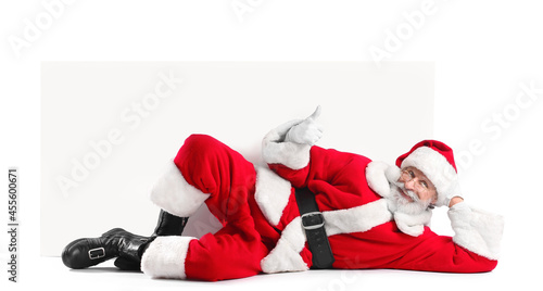 Fotografie Lying Santa Claus with blank poster on white background