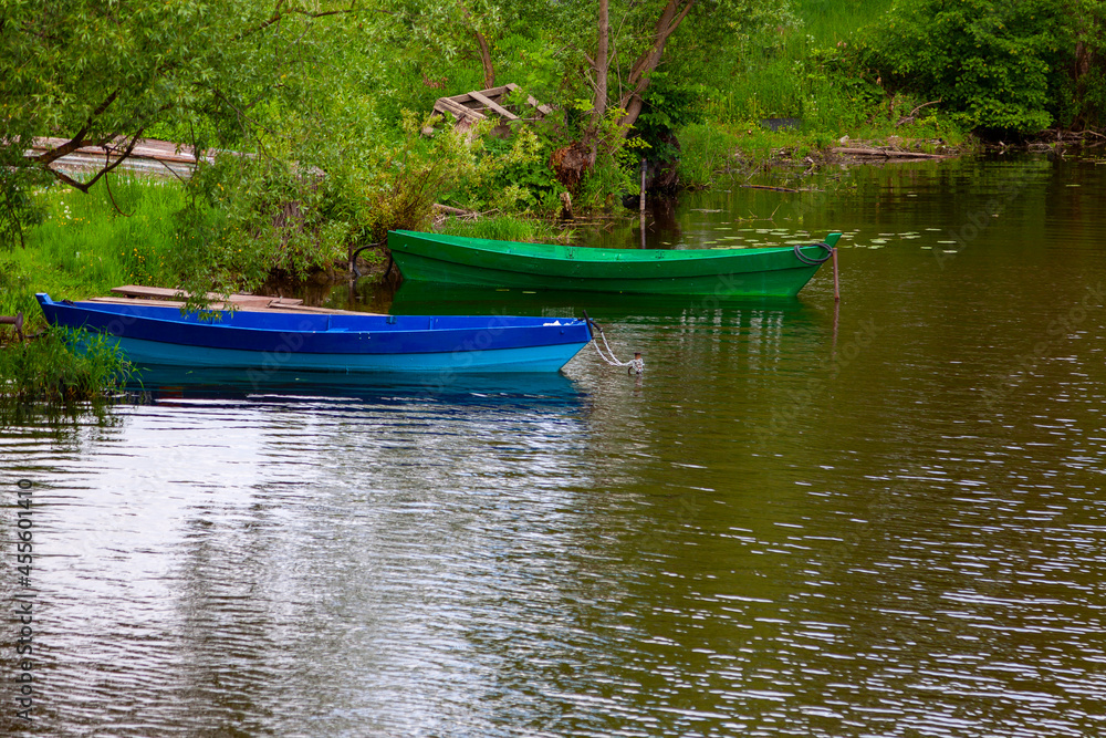 Two brightly painted fishing boats are anchored near the shore Two brightly painted fishing boats are anchored near the shore