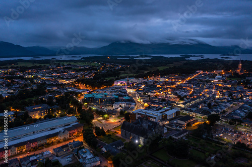 Aerial view of scenic tourist town of Killarney in county Kerry in Ireland with switched on lights under a cloudy early rise morning cloudy sky