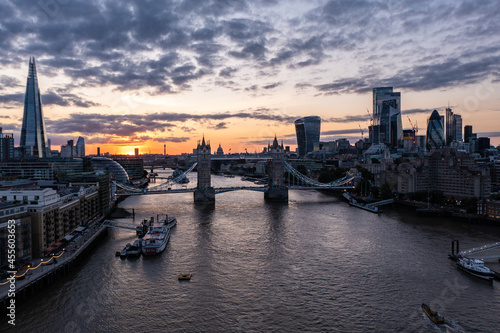 Establisher shot of the famous Tower Bridge over ocean surrounded with buildings and skyscrapers under a cloudy sunrise morning