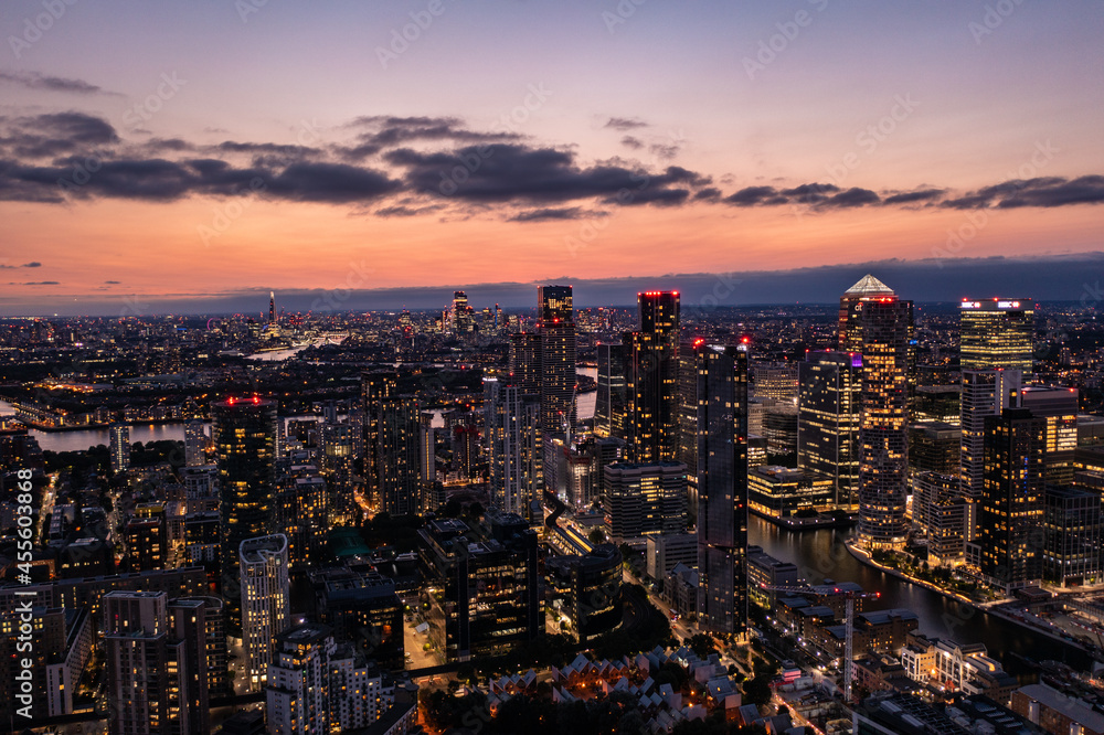 Panoramic aerial skyline view of east London at night with skyscrapers of Canary Wharf and beautiful colorful sky at background