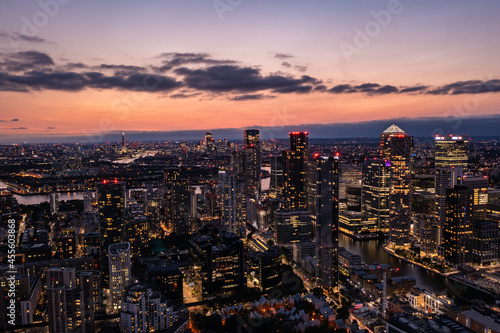 Panoramic aerial skyline view of east London at night with skyscrapers of Canary Wharf and beautiful colorful sky at background
