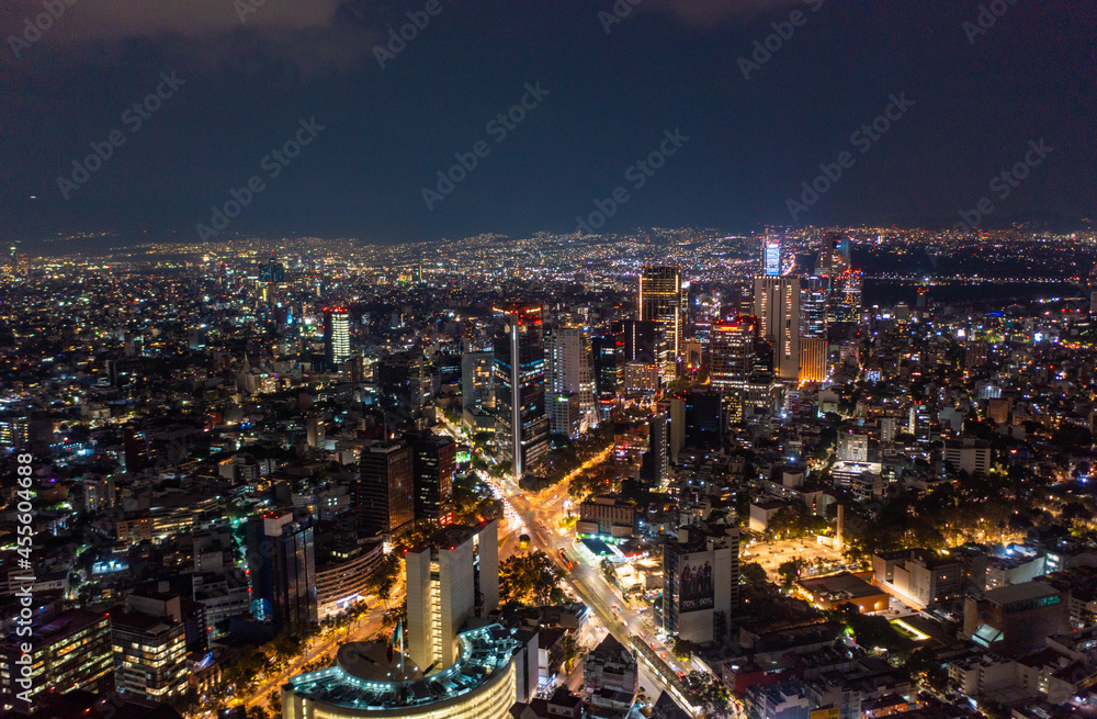 Obraz premium Aerial view of beautiful buildings with illuminated lightings shining in Mexico City against dark black sky at night