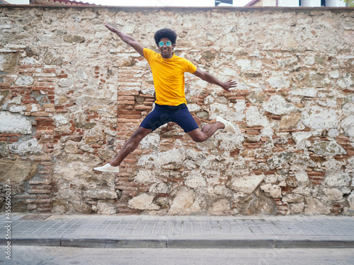 Smiling afro man jumping for joy on the street
