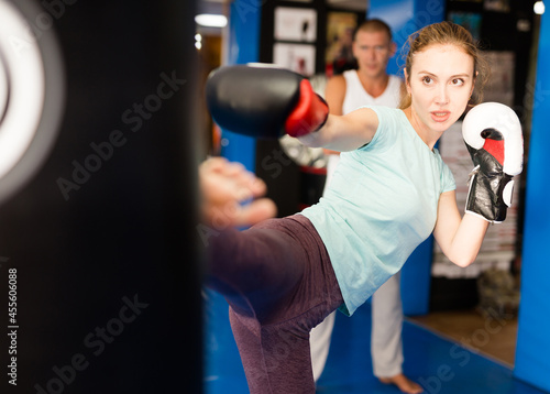 Young european boxer woman in boxing gloves is practicing different kicks at gym © JackF