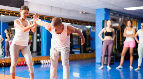 Active asian woman is practicing self-defence moves in pair with her trainer at gym