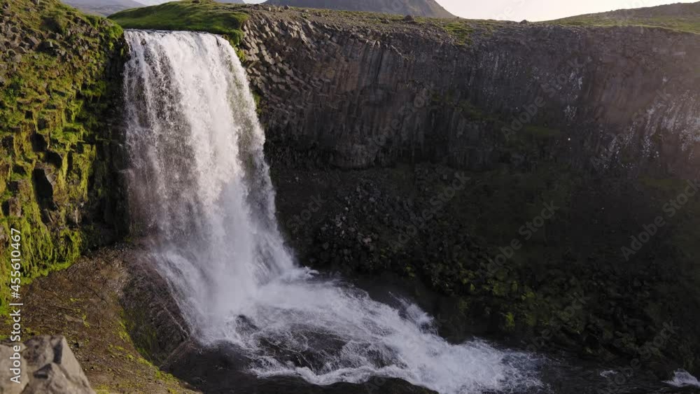 Waterfall over unique rock formations with lush green grass (Slow Motion) Waterfall over unique rock formations with lush green grass (Slow Motion)