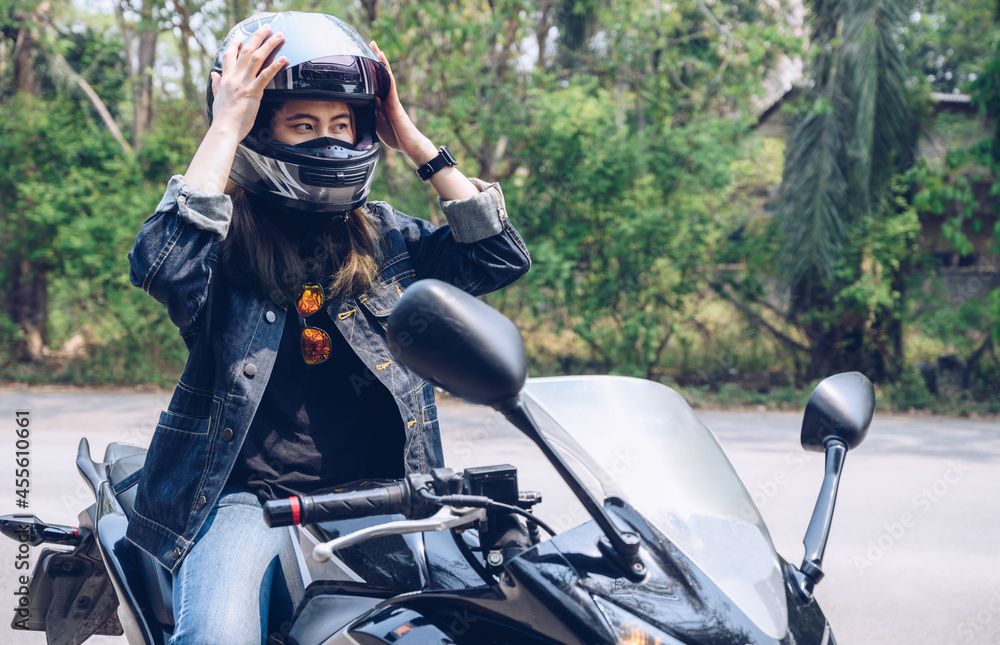 Confidence Asian woman wearing a motorcycle helmet before riding. Helmets  contribute to motorcycle safety by protecting the rider's head. Stock Photo  | Adobe Stock