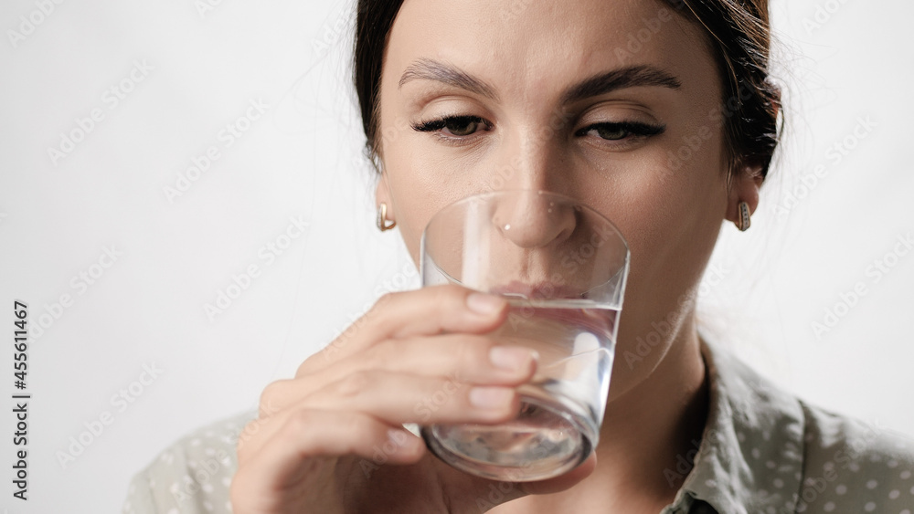 Woman is drinking water. Woman on white background drinks water from glass. Close-up Woman is drinking water. Woman on white background drinks water from glass. Close-up