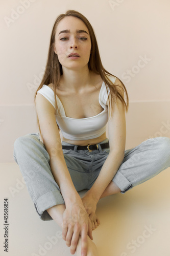 Obraz na plátně Image of attractive young woman sitting on studio floor barefooted in trendy rip