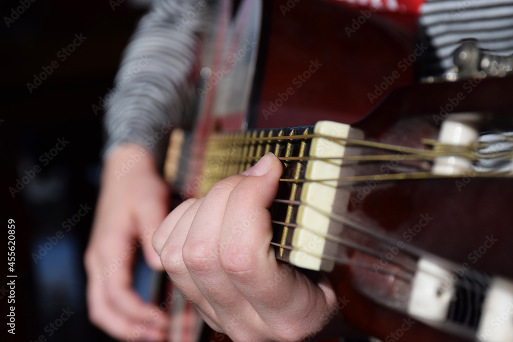 The hands of a young girl play the guitar