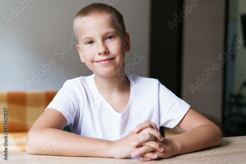 Portrait of cute generation z schoolboy in white t-shirt talking to webcam during video call. Child studies online, studies at home, using gadget for virtual conversation with teacher. Screen capture