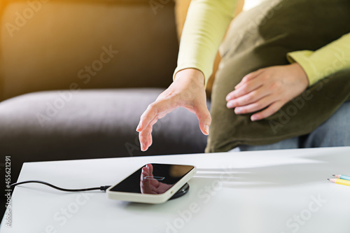 Woman hands plugging a charger in a smart phone. Charging Smartphone with Wireless Charging Pad at Home
