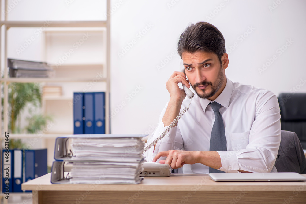 Young male employee and too much work in the office Young male employee and too much work in the office