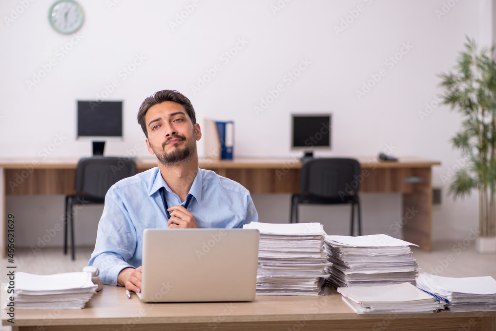 Young male employee and too much work in the office Young male employee and too much work in the office