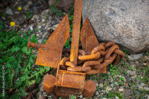 An old rusty anchor is lying on the ground.