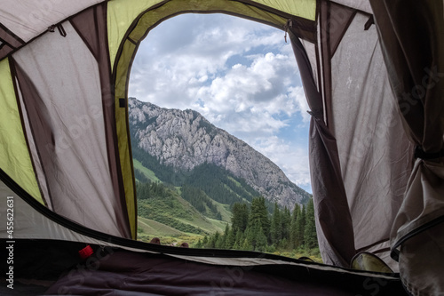 Beautiful view from tent to mountains with cloudy blue sky. Summer holiday background. Lifestyle concept. Travel, vacation concept. Komirshi gorge in Kazakhstan.