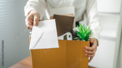 Business woman sending resignation letter and packing Stuff Resign Depress or carrying business cardboard box by desk in office. Change of job or fired from company photo