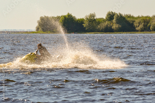 A woman are racing on a jetski while splashing water. Blurred into motion. Defocused image. © Helena