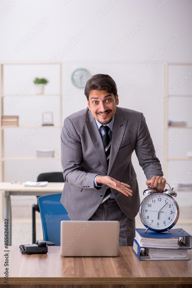 Young male employee in time management concept Young male employee in time management concept