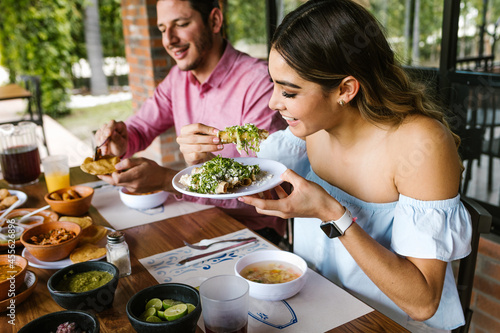 young latin woman eating mexican tacos on a restaurant terrace in Mexico Latin America, feeling happy on a summer day