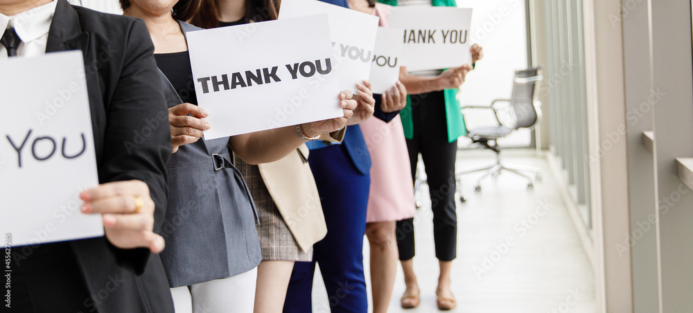 Group of businesspeople join together greeting and hold thank you word for sign of thankfulness to someone in modern office. Idea for good teamwork feeling declaration and support for colleagues