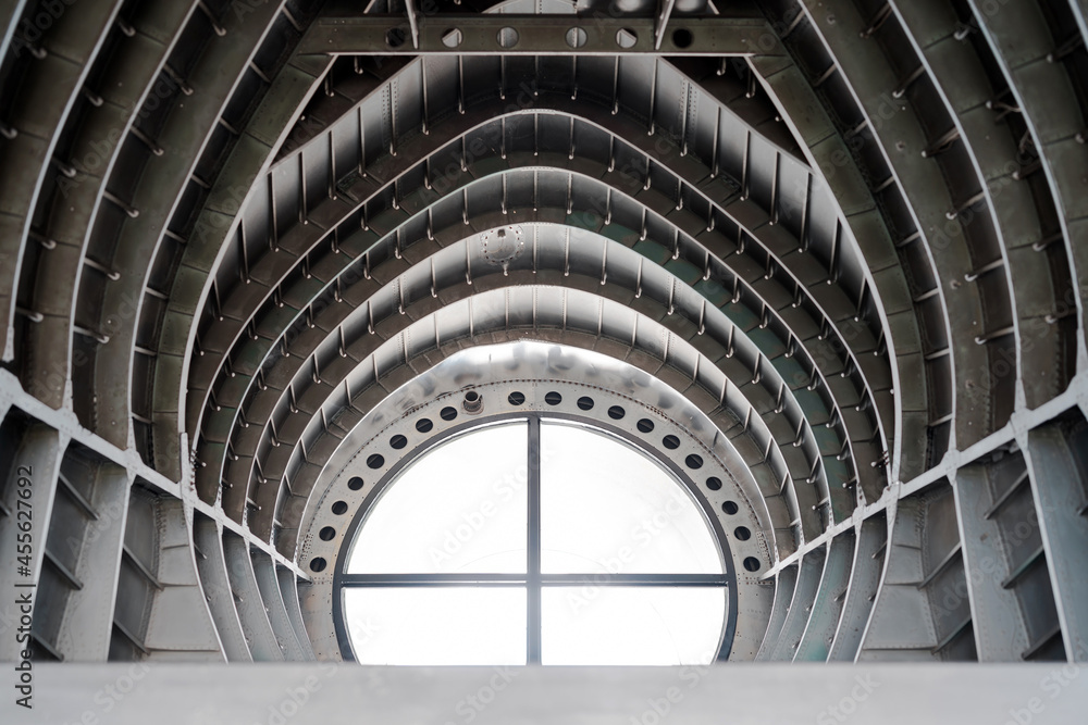 Fototapeta premium modern retro ceiling metal steel arch wall with round window light, part inside old airplane. abstract background 