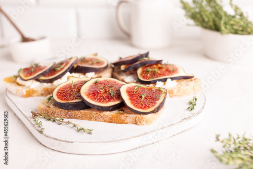 Breakfast with sweet bruschettas with figs and honey on a white plate