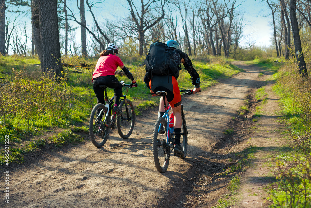 Couple cycling on the dirt road in the woods
