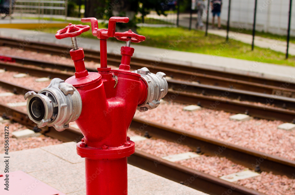 Top view of the single red fire hydrant, which standing on the pavement near rails. Kyiv Children's Railway in Syretsky Park. Blurred background Top view of the single red fire hydrant, which standing on the pavement near rails. Kyiv Children's Railway in Syretsky Park. Blurred background