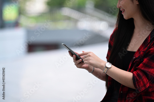 Happy woman using smart phone and standing on a city street.