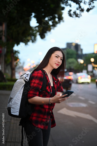 Young Asian woman waiting for taxi for transporting on road in city.